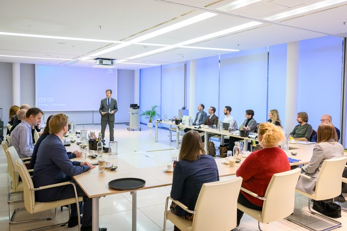 Öffnet eine Lightbox: In einem Veranstaltungsraum wird eine Ansprache gehalten 